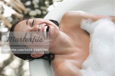 Belle jeune femme, prendre un bain de bulles et souriant