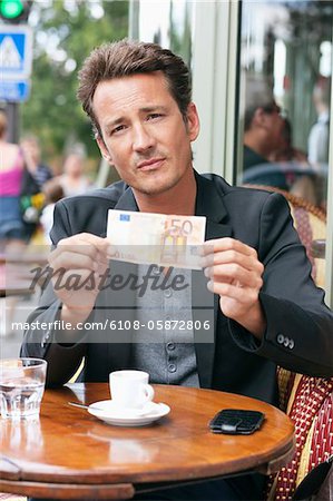 Homme montrant un billet en euros 50 dans un restaurant, Paris, Ile-de-France, France