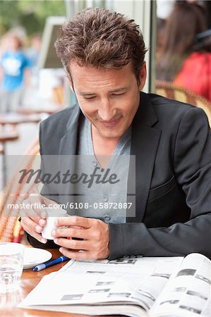 Homme lisant un magazine dans un restaurant, Paris, Ile-de-France, France