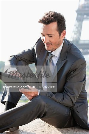 Businessman using a digital tablet with the Eiffel Tower in the background, Paris, Ile-de-France, France