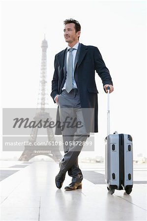 Businessman standing with luggage with the Eiffel Tower in the background, Paris, Ile-de-France, France