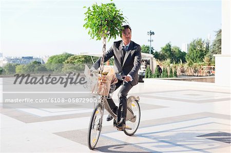 Businessman carrying a plant on a bicycle, Eiffel Tower, Paris, Ile-de-France, France