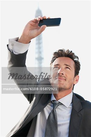 Homme d'affaires de prendre une photo de lui-même avec la tour Eiffel en arrière-plan, Paris, Ile-de-France, France