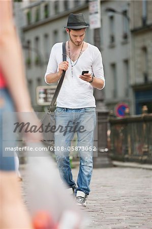 Mann zu Fuß auf der Straße und SMS-Nachrichten mit einem Mobiltelefon, Paris, France, Frankreich