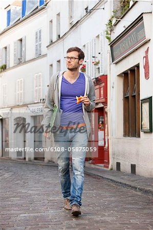 Man carrying a file while eating food, Paris, Ile-de-France, France
