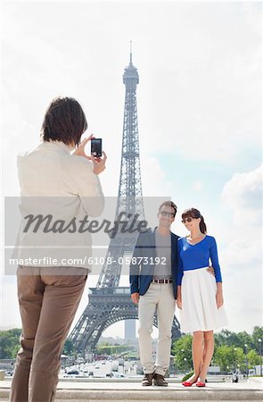 Femme de prendre une photo du couple avec la tour Eiffel en arrière-plan, Paris, Ile-de-France, France