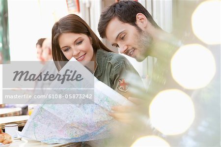 Couple assis dans un café de trottoir et la lecture d'une carte, Paris, Ile-de-France, France