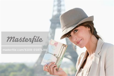 Woman showing a postcard with the Eiffel Tower in the background, Paris, Ile-de-France, France