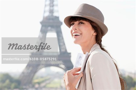 Woman holding a guide book with the Eiffel Tower in the background, Paris, Ile-de-France, France