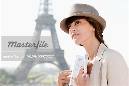 Woman holding a guide book with the Eiffel Tower in the background, Paris, Ile-de-France, France