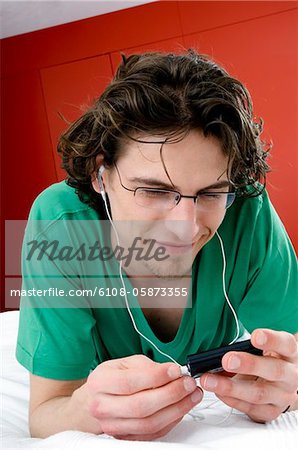 Homme à l'écoute de MP3 player, couché sur un lit