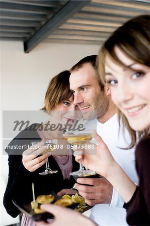 deux femmes et un homme tenant des verres de champagne