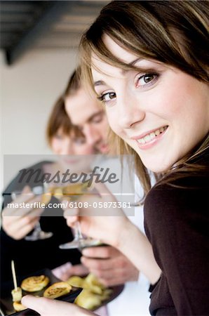 Femme souriant à la caméra, tenant des verres de champagne