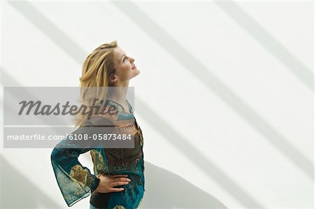 Young woman in profile looking up, arms akimbo