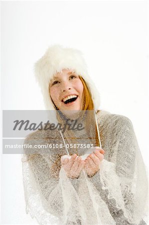 Jeune femme tenant la neige dans ses mains et souriant