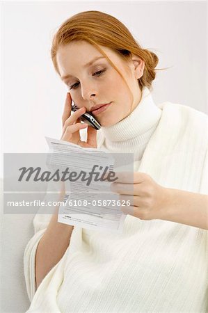 Gros plan d'une enceinte jeune femme lisant un rapport médical et de parler sur un téléphone mobile