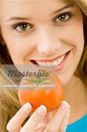 Portrait of a young woman holding a tomato and smiling