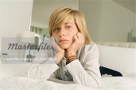 Teenage boy lying on the bed and looking serious