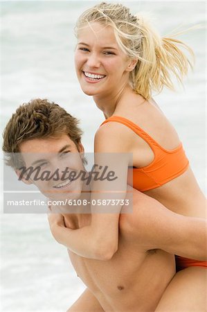 Man giving Woman piggyback Ride am Strand