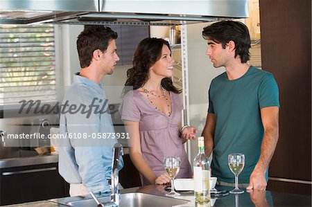 Trois amis, boire du vin dans la cuisine