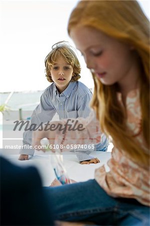 Girl playing with toys and a boy looking at her