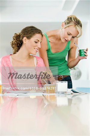 Two women reading a magazine at a dining table