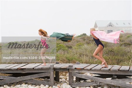 Two girls running on a boardwalk
