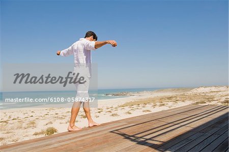 Homme marchant sur un trottoir de bois sur la plage