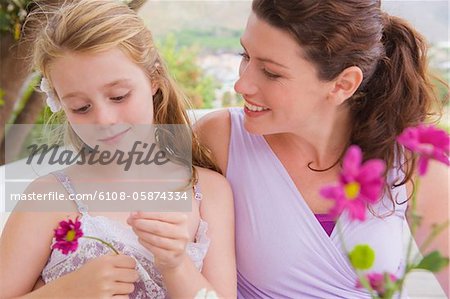 Close-up of a woman smiling with her daughter holding a flower
