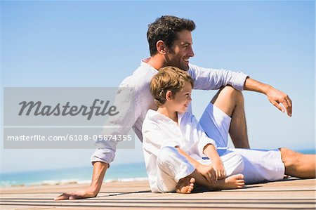 Man sitting on a boardwalk with his son
