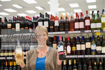 Woman showing two wine bottles in a supermarket