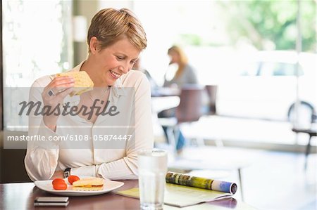 Businesswoman sitting in a restaurant and reading a magazine