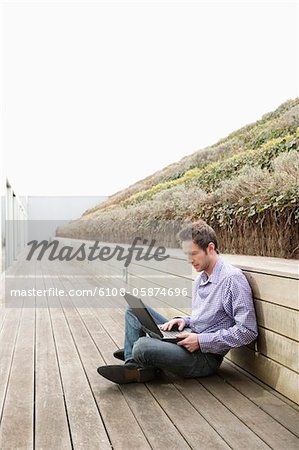 Mann mit einem Laptop auf einer Promenade