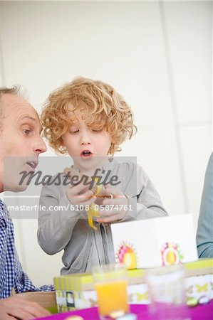 Garçon ouvrant son cadeau d'anniversaire avec son grand-père à côté de lui