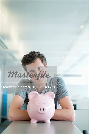 Businessman smiling near a piggy bank