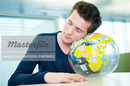 Businessman napping on a globe in an office