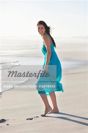 Fröhliche junge Frau, stehend auf einem Strand
