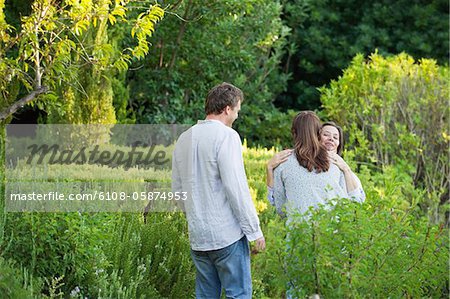 Mature couple hugging their mother in a garden