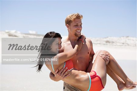 Man carrying woman on the beach