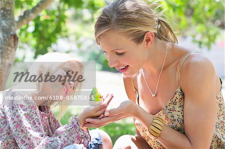 Little girl and her mother looking at toy outdoors
