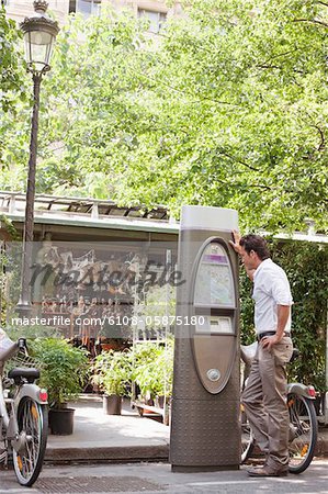 Homme regardant une carte dans une machine de billet, Paris, Ile-de-France, France