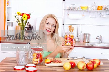 Smiling young woman making canned peaches