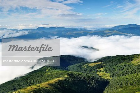 Landscape with mountains and forests under morning sky with clouds