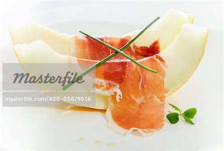 Delicious sliced melon and bacon on white plate