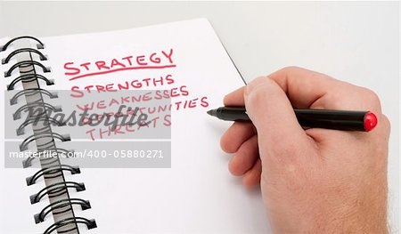 SWOT Analysis - Close up of Hand With Red Marker and Open Notebook