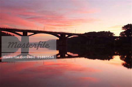 Railway bridge connecting river banks with reflection at sunrise
