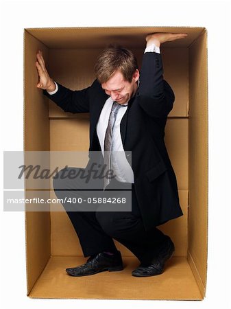 Well dressed businessman in a tight cardboard box isolated on white background