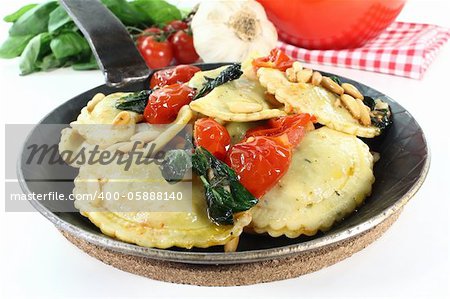 Rocket and Ricotta Cappelletti with pine nuts, tomatoes and basil in a pan
