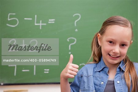 Schoolgirl with the thumb up in front of a blackboard