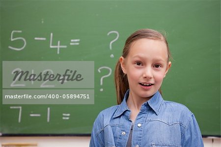 Smiling schoolgirl posing in front of a blackboard